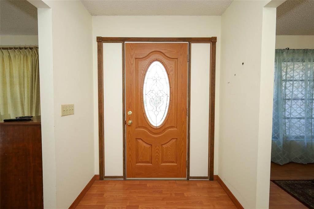 An entryway with a wood-paneled door leads into a dining room with a wooden hutch — 504 RIDGEWOOD STREET, ALTAMONTE SPRINGS, FL