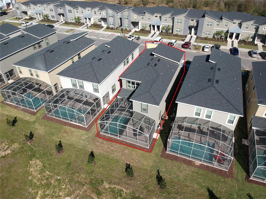 An aerial view shows a two-story house with a screened-in pool and patio area — 8974 CABOT CLIFFS DRIVE, DAVENPORT, FL