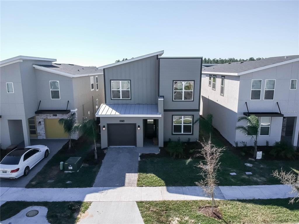 An exterior view of a two-story modern house with a gray facade and attached garage — 8974 CABOT CLIFFS DRIVE, DAVENPORT, FL