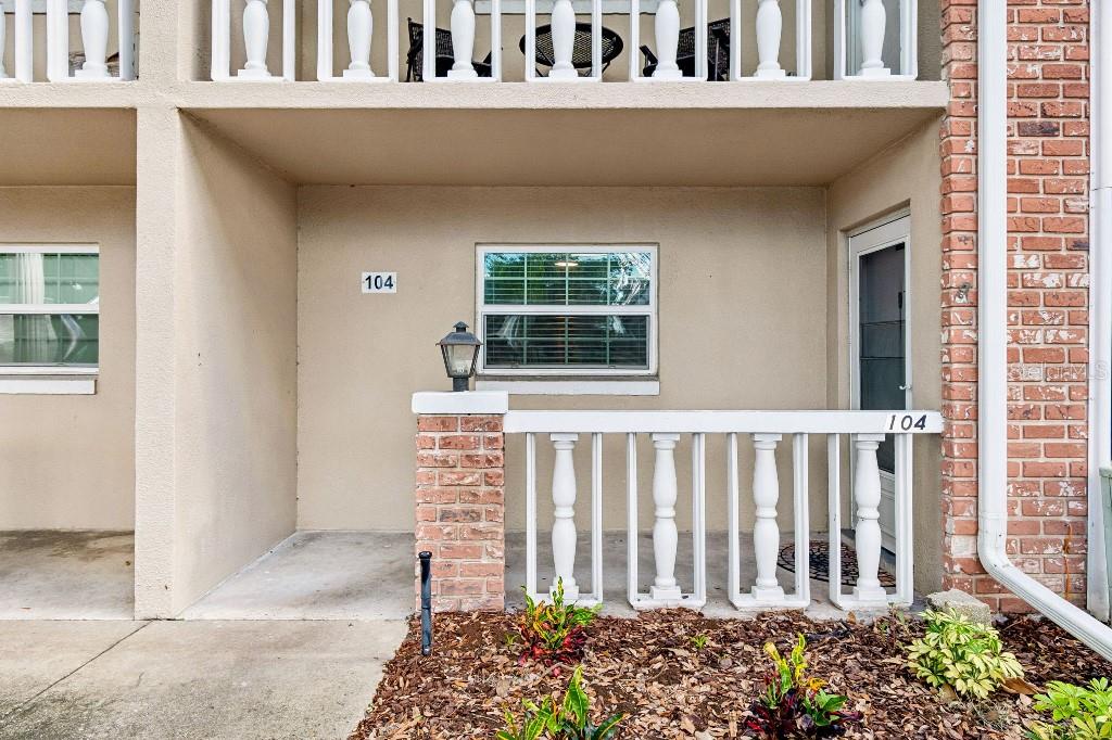 The exterior of a ground-level unit features a brick-accented porch, white railings, and a window — 2500 LEE ROAD UNIT 104, WINTER PARK, FL