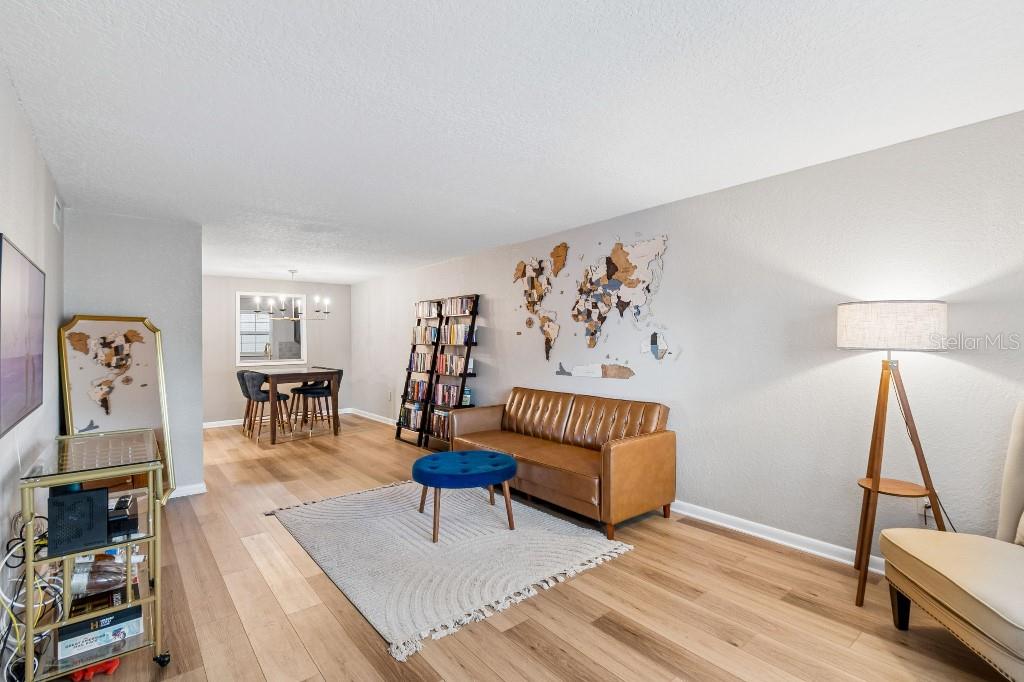 A living room features a brown leather sofa, a blue ottoman, and a world map wall — 2500 LEE ROAD UNIT 104, WINTER PARK, FL
