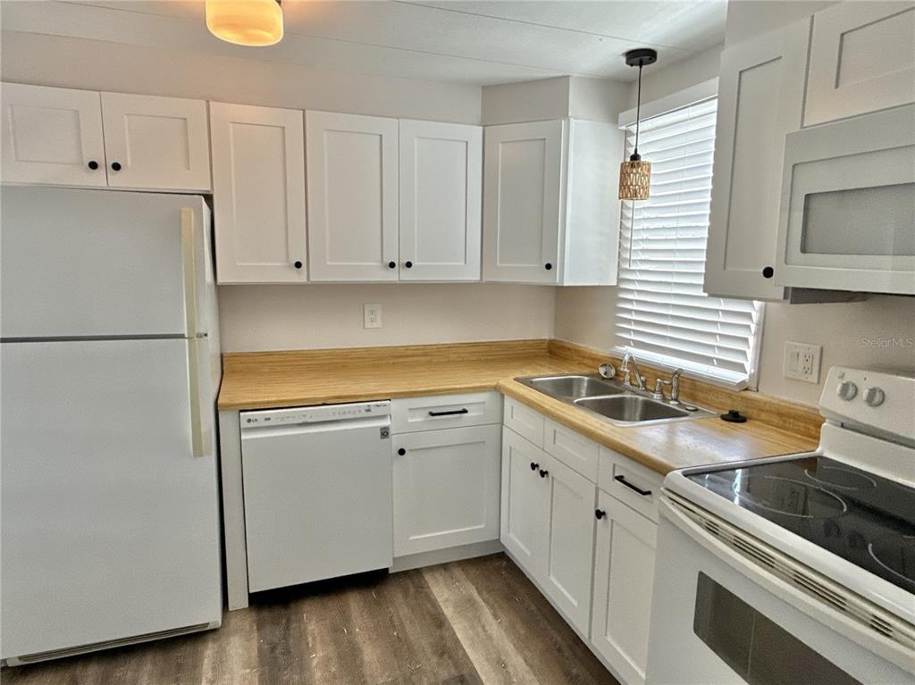 A kitchen features white cabinets, a light wood countertop, and white appliances — 347 MOUNT SAXON AVENUE NE UNIT 324, ST PETERSBURG, FL