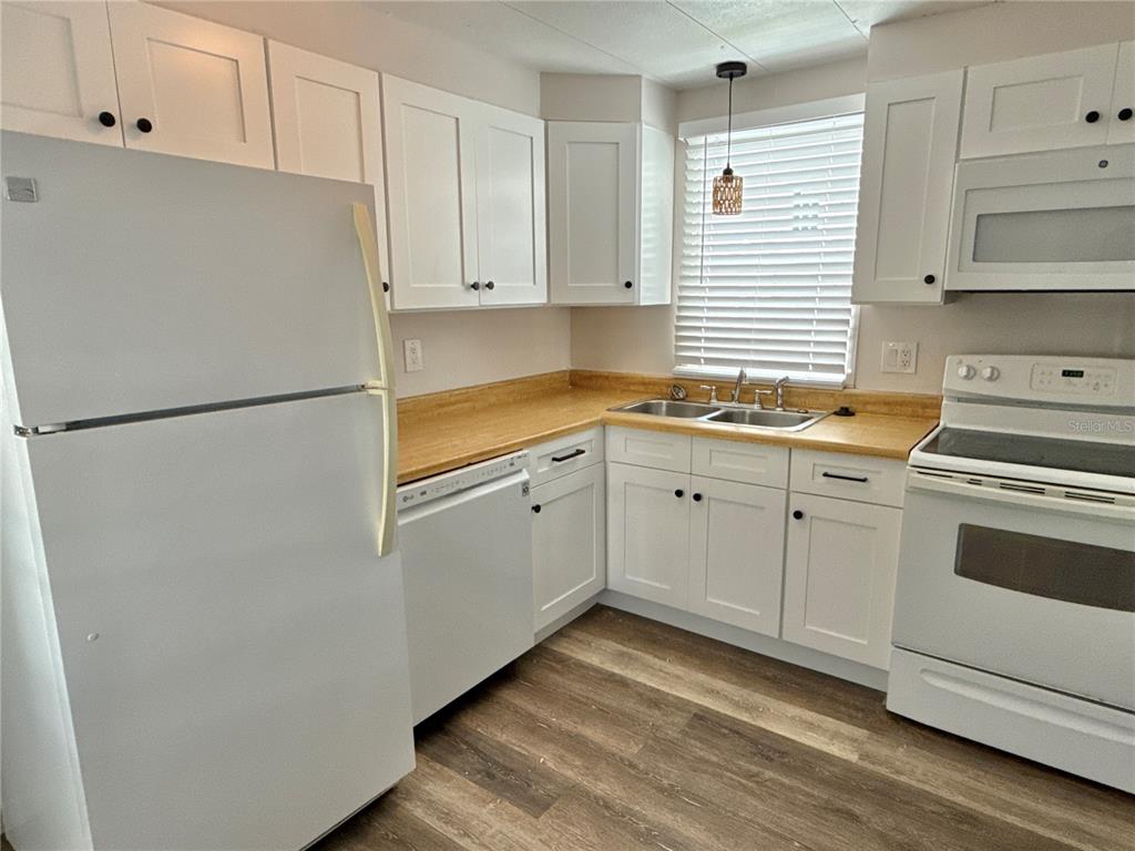 A kitchen features white cabinets, a light wood countertop, white appliances, and wood-look flooring — 347 MOUNT SAXON AVENUE NE UNIT 324, ST PETERSBURG, FL
