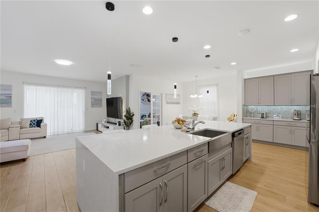 A modern kitchen with a large white quartz island overlooks an open-concept living area — 6825 WILSON HAMMOCK AVENUE, GROVELAND, FL