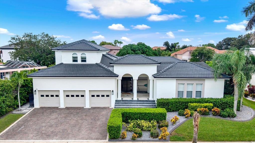 A white two-story house with a three-car garage and a dark tiled roof — 1424 JUMANA LOOP, APOLLO BEACH, FL