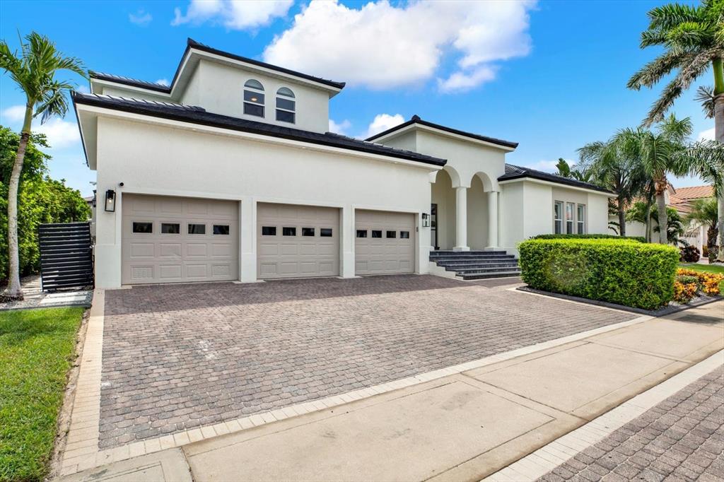 A white two-story house features a three-car garage and a paved driveway — 1424 JUMANA LOOP, APOLLO BEACH, FL