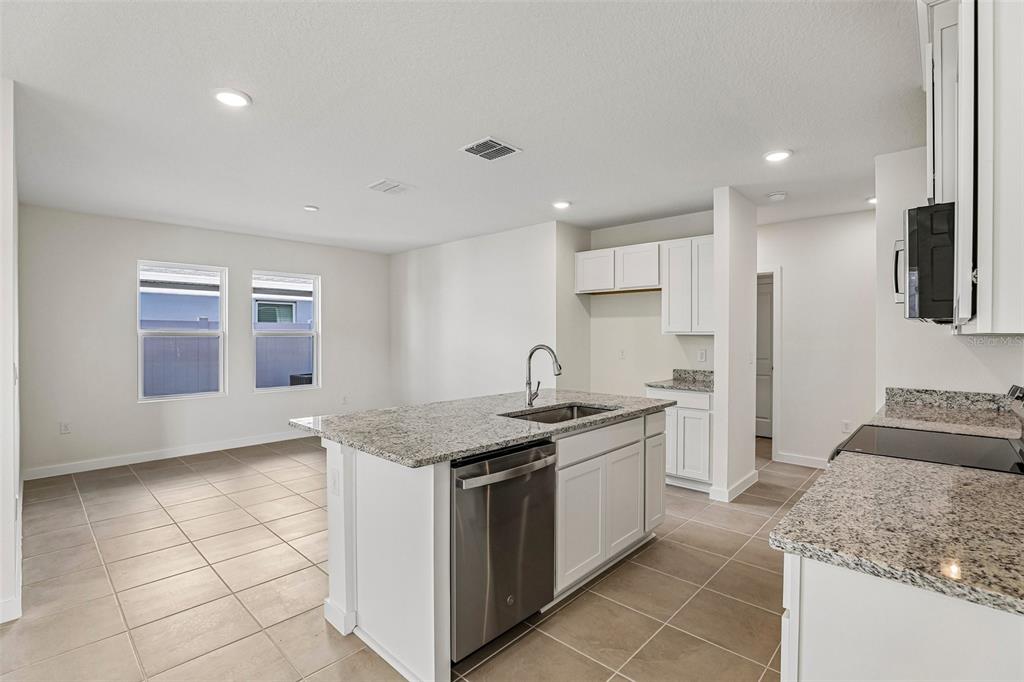 A kitchen with white cabinets, granite countertops, stainless steel appliances, and tile flooring — 2720 MEADOW CREST DRIVE, ST CLOUD, FL