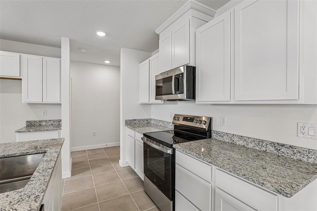A kitchen features white cabinets, granite countertops, and stainless steel appliances — 2720 MEADOW CREST DRIVE, ST CLOUD, FL