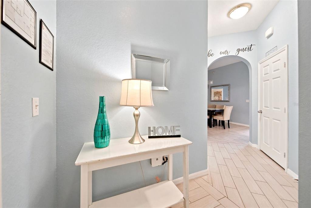 A light blue entryway features a white console table, a lamp, and a laundry room door — 3050 PIRATES RETREAT COURT UNIT 408, KISSIMMEE, FL