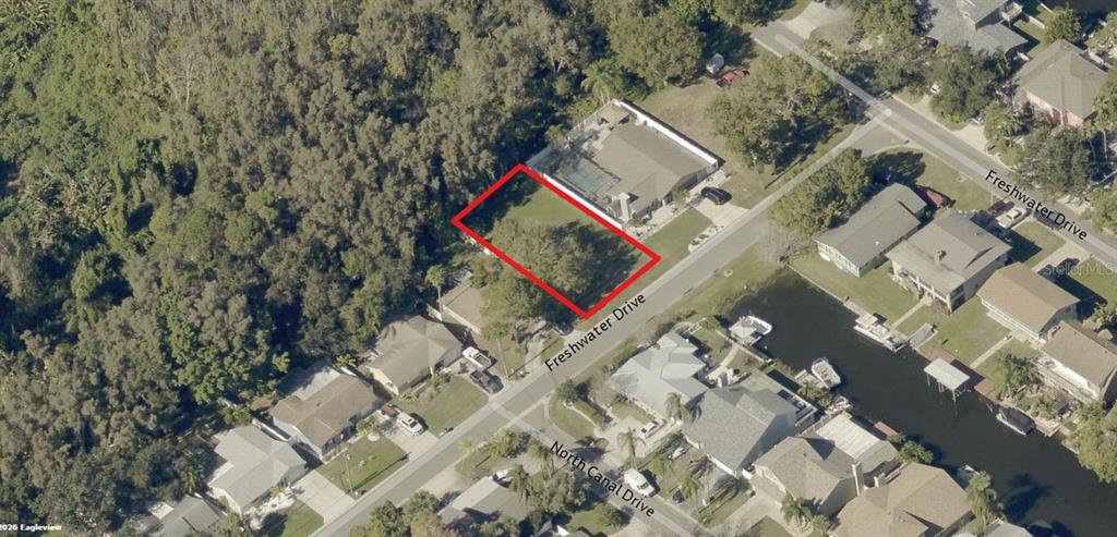 An aerial view shows a vacant residential lot outlined in red along a suburban street — 10 FRESHWATER DRIVE, PALM HARBOR, FL