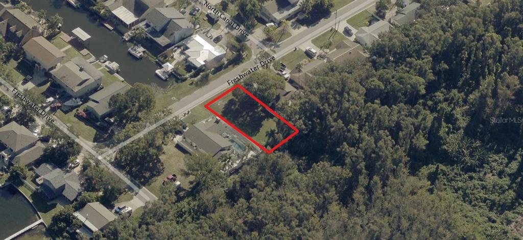 An aerial view shows a vacant rectangular residential lot outlined in red along a road — 10 FRESHWATER DRIVE, PALM HARBOR, FL