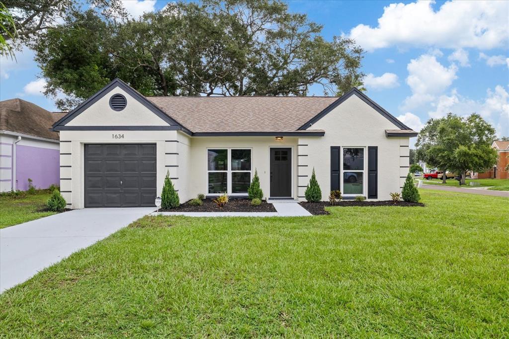 A single-story house with a cream stucco exterior, dark trim, and an attached garage — 1634 CROSSRIDGE DRIVE, BRANDON, FL