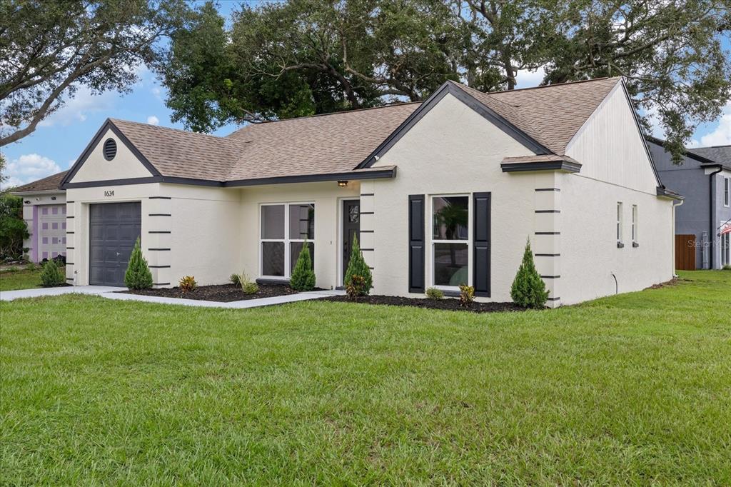 A single-story house with cream stucco walls, dark trim, and a front-facing garage — 1634 CROSSRIDGE DRIVE, BRANDON, FL