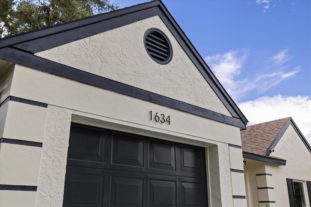 The exterior of a house features a garage door, a gable roof, and house number 1634 — 1634 CROSSRIDGE DRIVE, BRANDON, FL