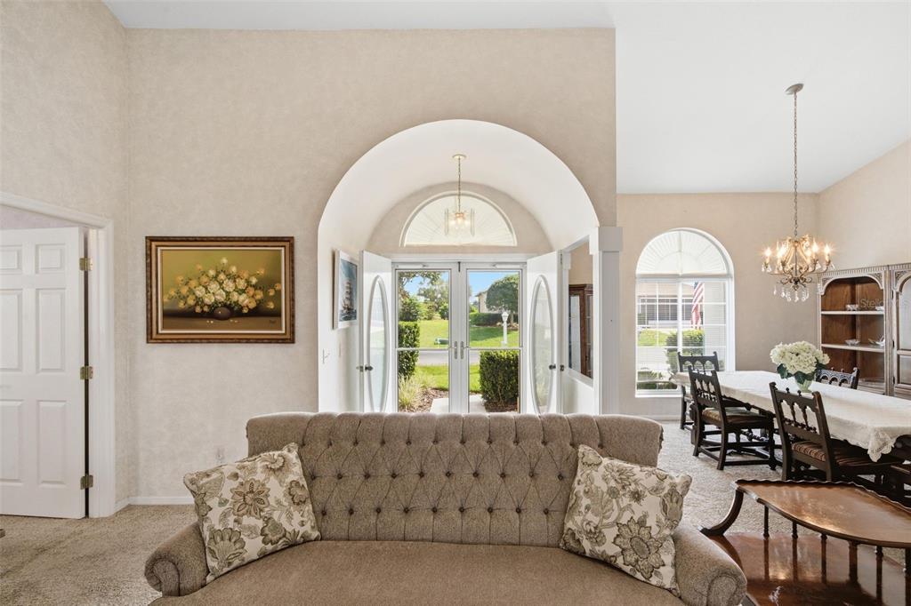 A living room with a tufted sofa, arched entryway, and an adjacent dining area — 2160 NW 50TH CIRCLE, OCALA, FL