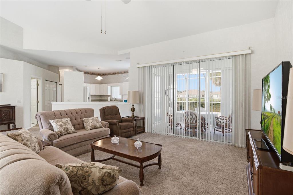 A living room with beige carpet, a sofa, a recliner, and sliding glass doors to a patio — 2160 NW 50TH CIRCLE, OCALA, FL