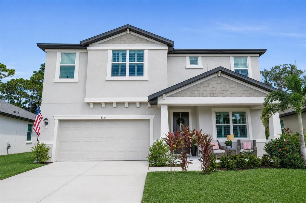 A two-story suburban house with a light-colored stucco exterior, a garage, and a front porch — 8219 TEA OLIVE TERRACE, PALMETTO, FL