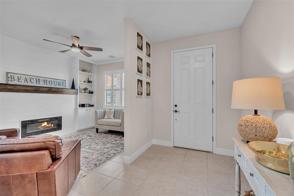 A tiled entryway leads into a living room featuring a fireplace and built-in shelving — 8219 TEA OLIVE TERRACE, PALMETTO, FL