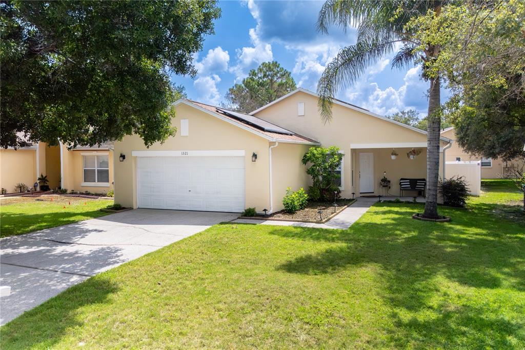 A single-story house with a beige exterior, a two-car garage, and a front porch — 1321 WHITEWOOD WAY, CLERMONT, FL