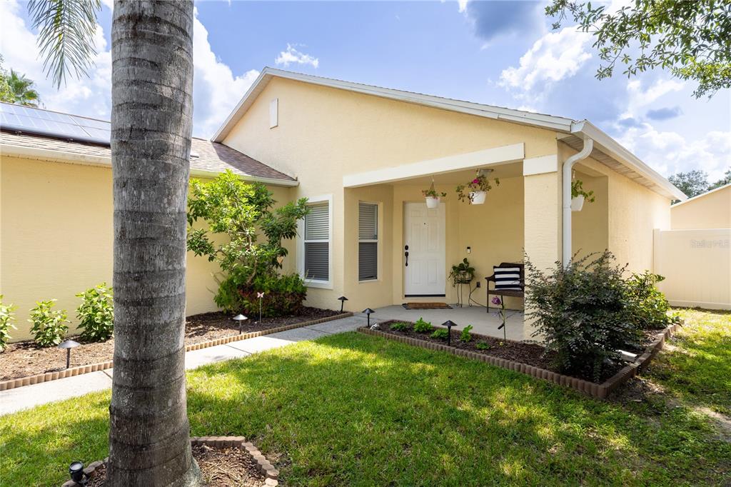 The exterior of a yellow house features a covered front porch and a landscaped yard — 1321 WHITEWOOD WAY, CLERMONT, FL