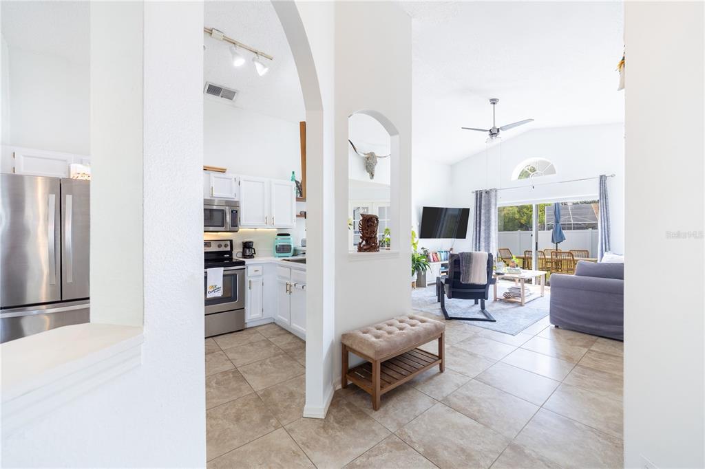 A view from a hallway into a kitchen and living room with tiled floors — 1321 WHITEWOOD WAY, CLERMONT, FL