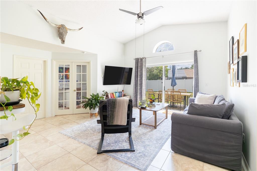 A living room with tile floors, a vaulted ceiling, a gray sofa, and a cow skull — 1321 WHITEWOOD WAY, CLERMONT, FL