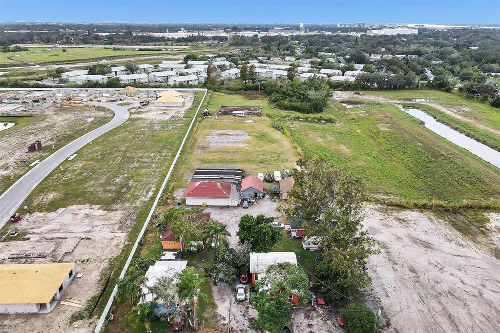 An aerial view shows several small houses and outbuildings surrounded by open land and construction — 1616 23RD STREET E, BRADENTON, FL