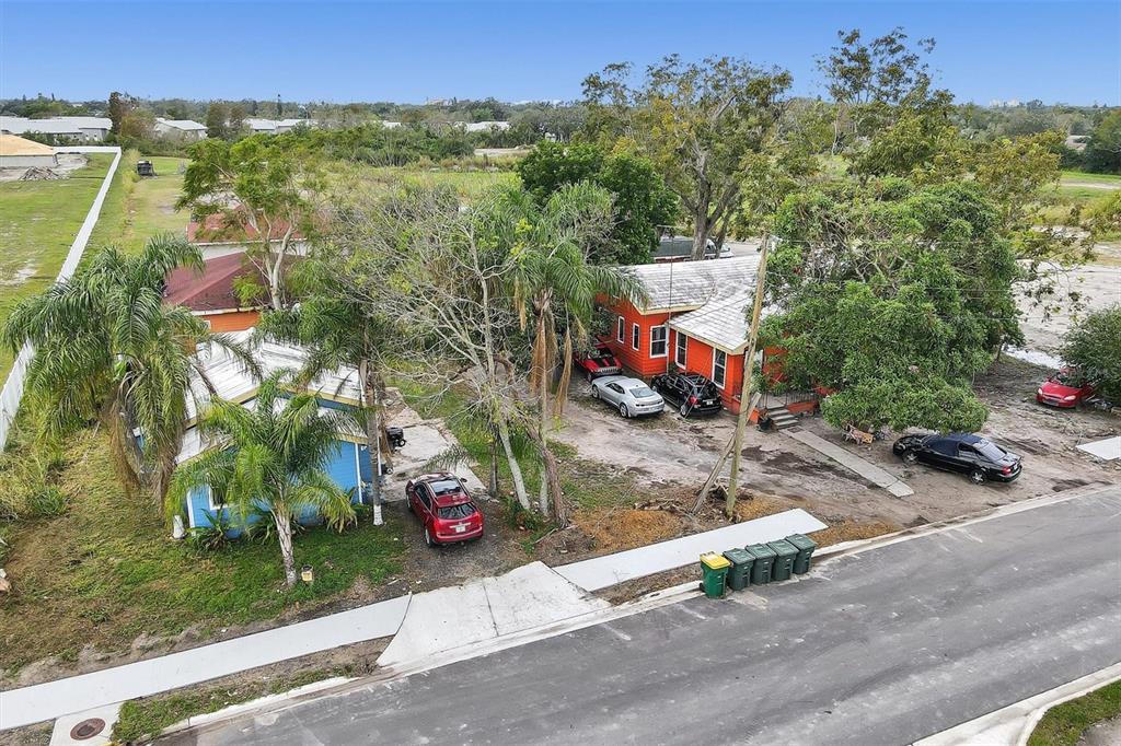 An aerial view shows two houses with multiple parked cars on a large, grassy lot — 1616 23RD STREET E, BRADENTON, FL