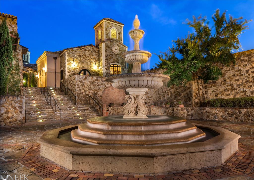 A stone fountain sits in the center of a courtyard with stairs leading to a building — 17114 MEDICI WAY, BELLA COLLINA, FL