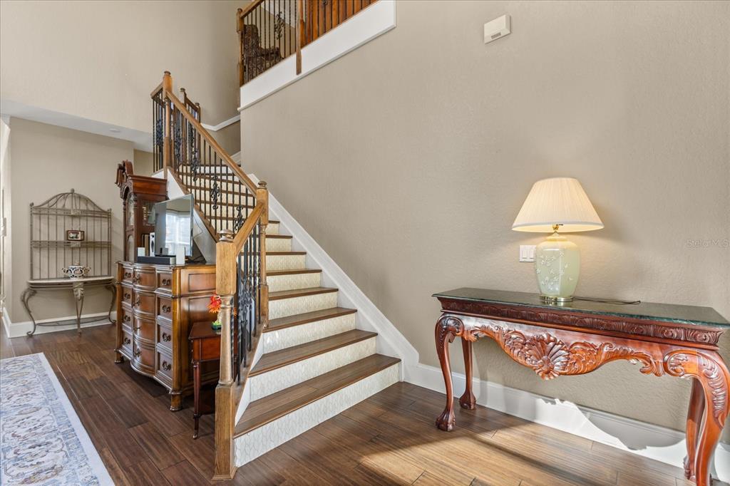 A foyer features a wooden staircase with patterned risers, a console table, and a dresser — 2450 DAHLGREN WAY, WINTER GARDEN, FL
