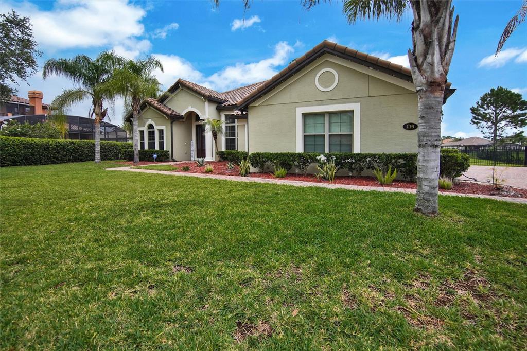 A single-story house with a tan stucco exterior, a tiled roof, and a front lawn — 119 ROSA BELLA VIEW, DEBARY, FL