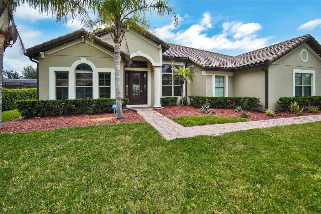 A single-story house with a beige stucco exterior, a tiled roof, and a palm tree — 119 ROSA BELLA VIEW, DEBARY, FL