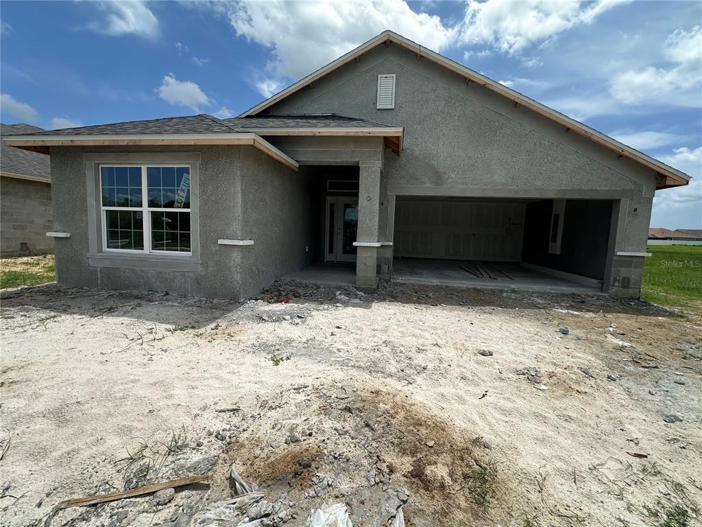 A newly constructed single-story house with a stucco exterior and an unfinished front yard — 12535 NE 48TH TERRACE, OXFORD, FL