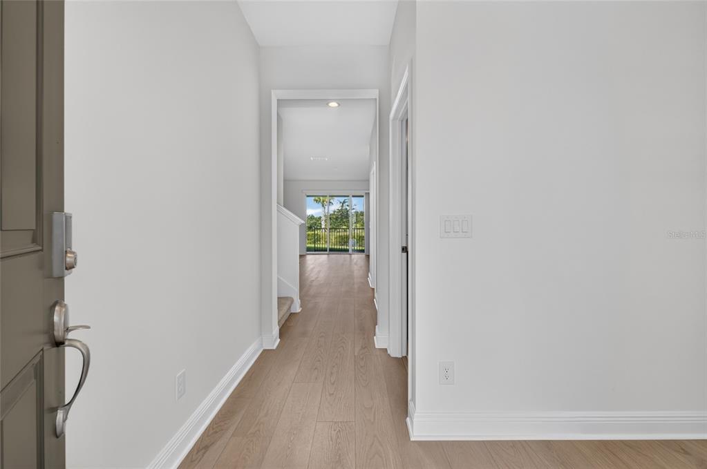 A view from an entryway looking down a hallway toward a living area with sliding doors — 7501 CATANIA LOOP, CLERMONT, FL