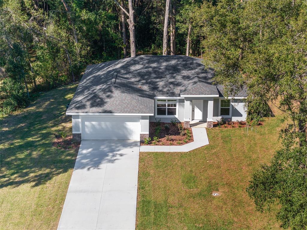 An aerial view of a single-story house with a gray roof, white garage, and landscaping — 10070 SW 192ND CIRCLE, DUNNELLON, FL