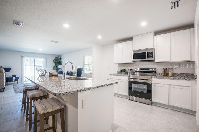 A kitchen with white cabinets, granite countertops, stainless steel appliances, and a large island — 16287 MELON ROAD, WEEKI WACHEE, FL