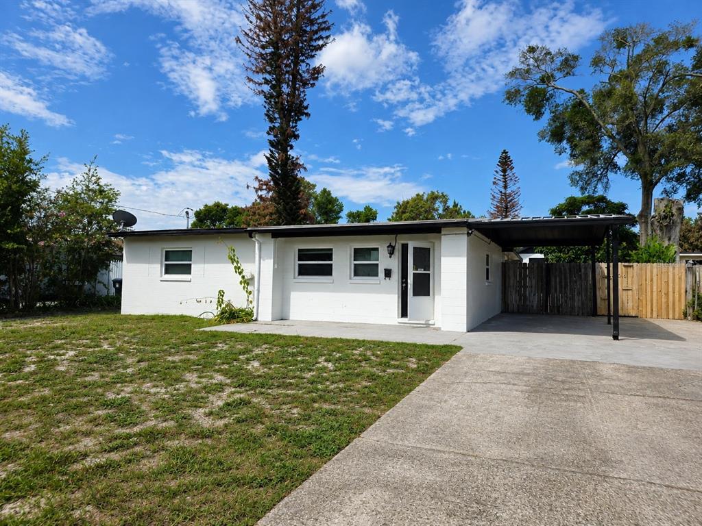 A white, single-story concrete block house features a front carport, a concrete driveway, and lawn — 606 EL VEDADO AVENUE, ORLANDO, FL