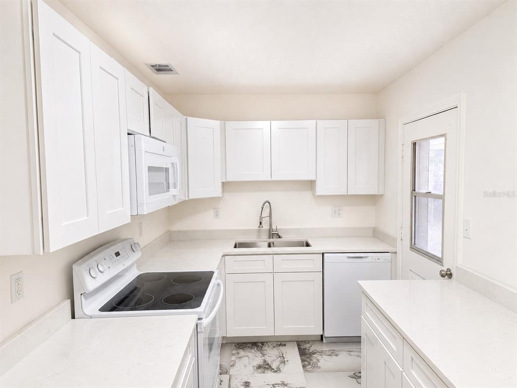 A kitchen with white cabinets, white countertops, a white stove, and a white dishwasher — 606 EL VEDADO AVENUE, ORLANDO, FL