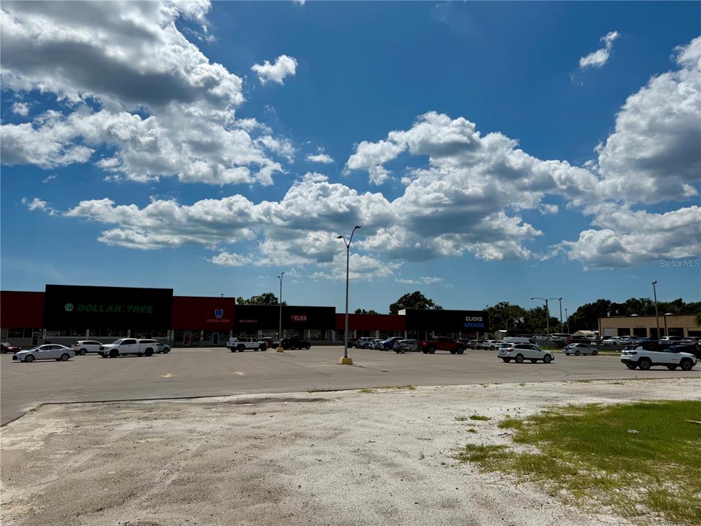 A large parking lot sits in front of a strip mall under a cloudy sky — 6812 14TH STREET W, BRADENTON, FL