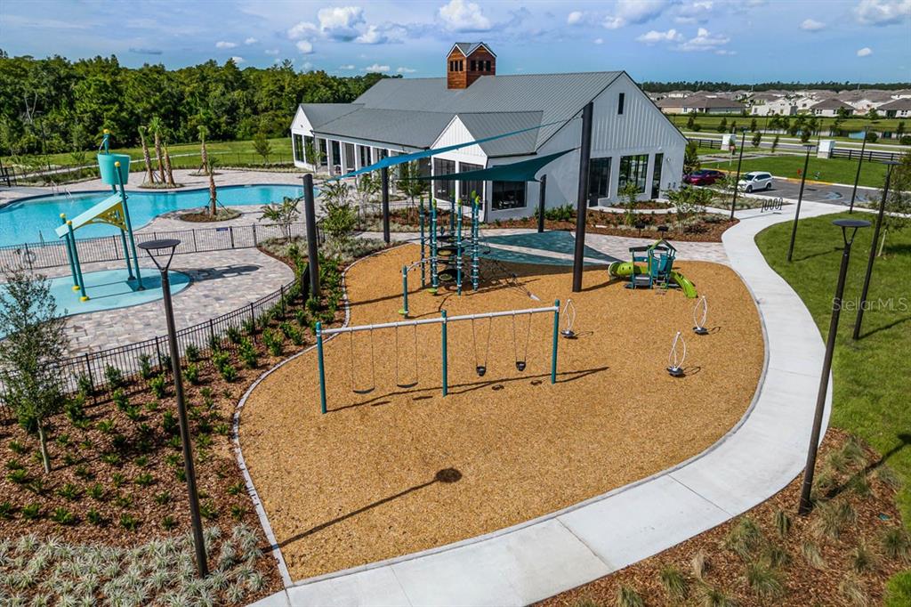 An outdoor playground with swings and a climbing structure sits beside a community swimming pool — 3157 HOUSE FINCH ROAD, ST CLOUD, FL
