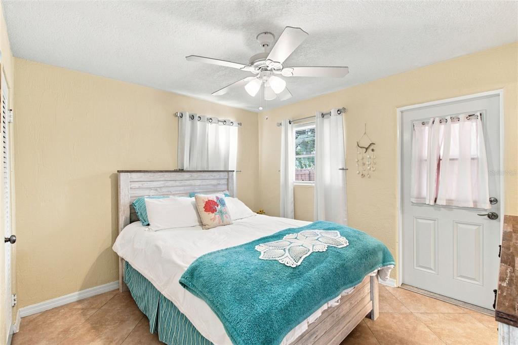 A bedroom features a bed with a teal throw, a ceiling fan, and tile flooring — 414 FLUSHING AVENUE, DAYTONA BEACH, FL
