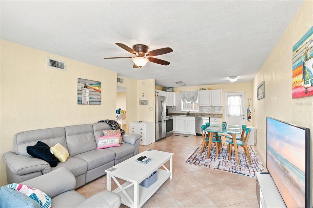 An open-concept living and dining area features a grey sofa, white coffee table, and kitchen — 414 FLUSHING AVENUE, DAYTONA BEACH, FL