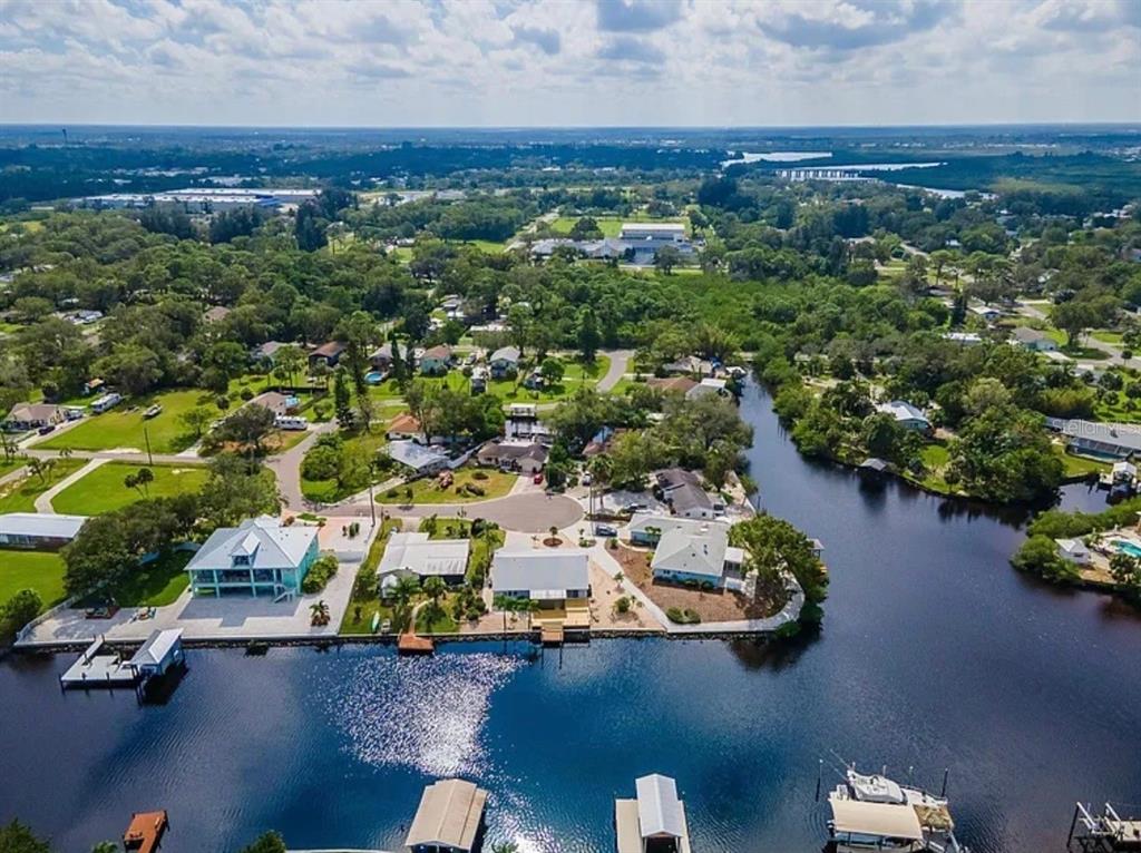 An aerial view shows waterfront houses along a canal surrounded by trees and green lawns — 805 LEISEY CIRCLE, RUSKIN, FL
