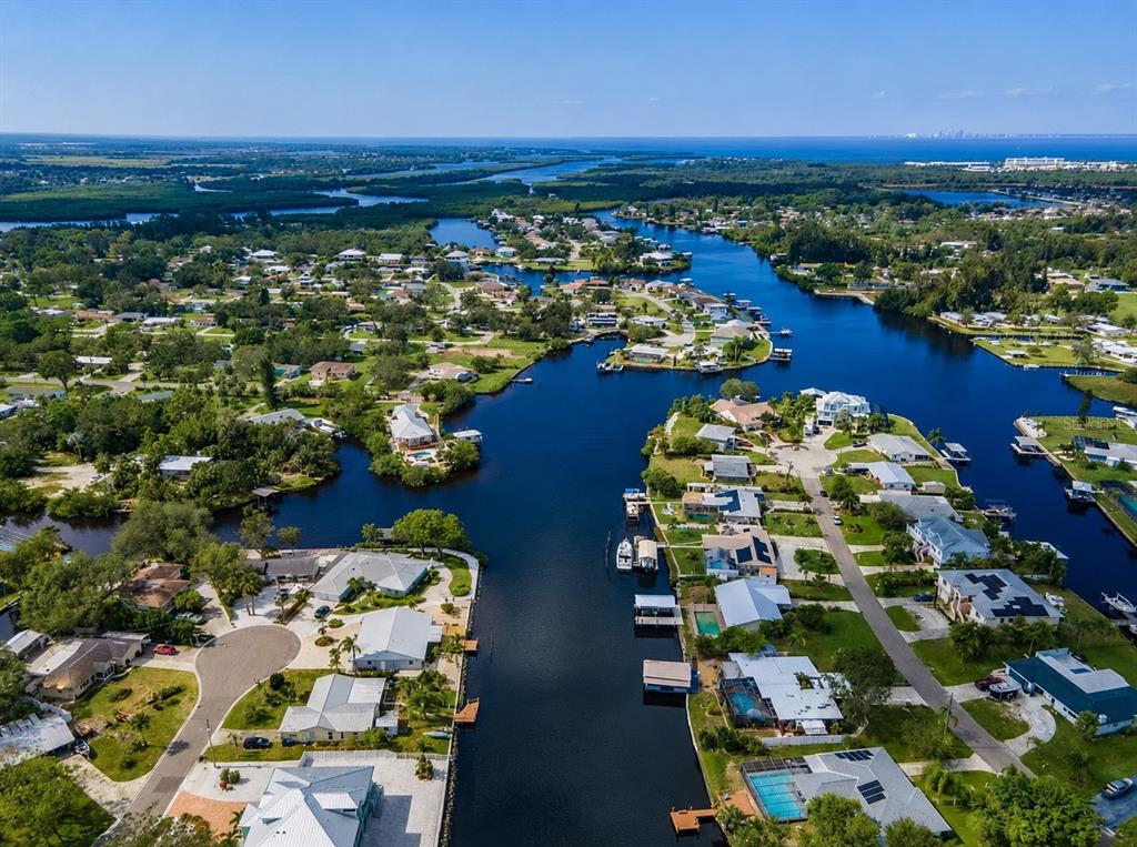 An aerial view of waterfront homes along a canal leading toward the open ocean — 805 LEISEY CIRCLE, RUSKIN, FL