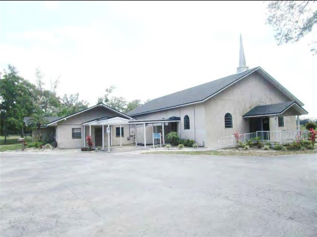 A light-colored church building with a steeple, a covered walkway, and a large paved parking lot — 1250 PIEDMONT WEKIWA ROAD, APOPKA, FL