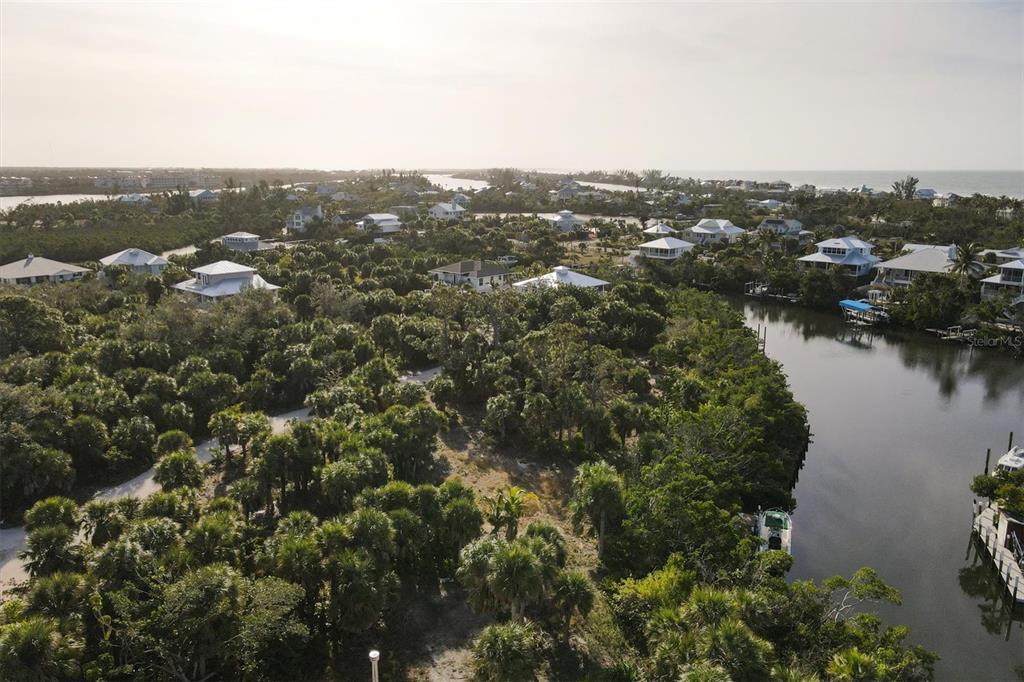An aerial view of a coastal neighborhood with houses nestled among trees along a canal — 21 BAYSHORE CIRCLE, PLACIDA, FL