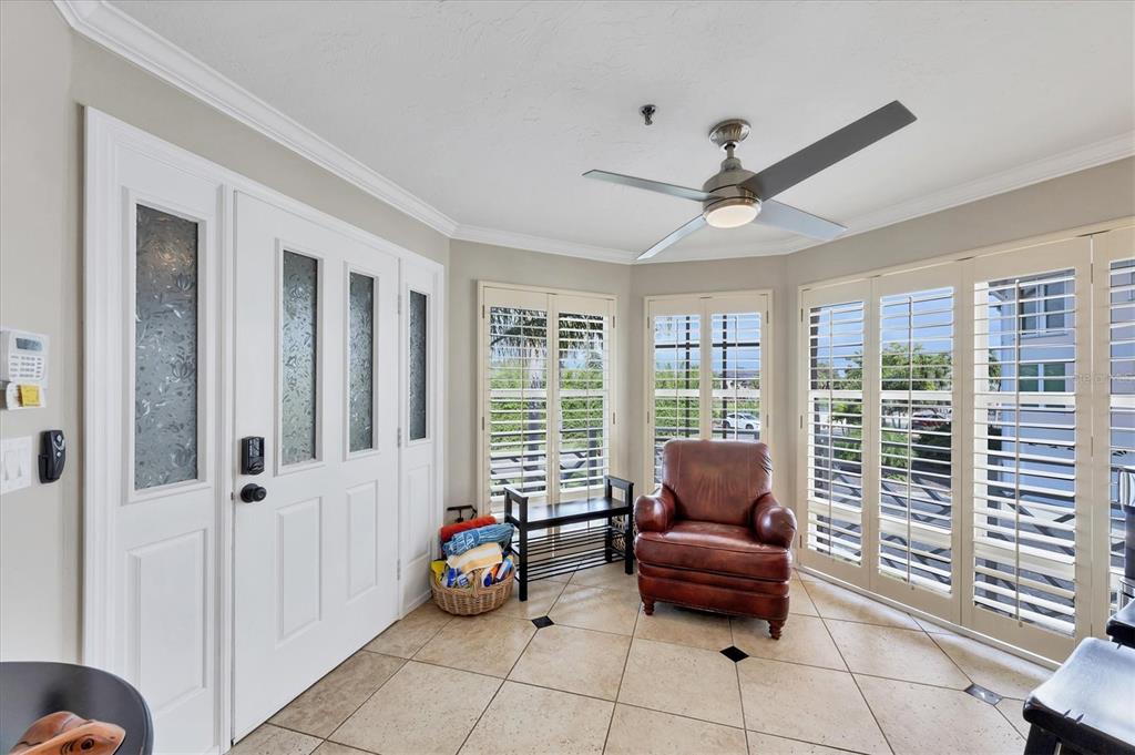 A sunroom with tile flooring, a leather armchair, plantation shutters, and a ceiling fan — 11000 PLACIDA ROAD UNIT 1601, PLACIDA, FL