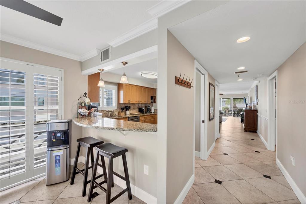 A kitchen with granite countertops and bar seating overlooks a tiled hallway and living area — 11000 PLACIDA ROAD UNIT 1601, PLACIDA, FL