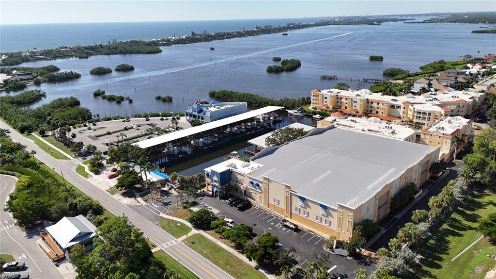 An aerial view shows a large commercial building, a boat storage facility, and a parking lot — 570 BLACKBURN POINT ROAD UNIT 23, OSPREY, FL