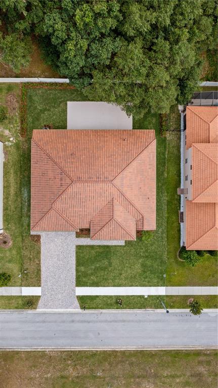 An aerial view shows a house with a terracotta tile roof, driveway, and backyard lawn — 12919 BRUNELLO CIRCLE, CLERMONT, FL